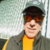 Photographer and site owner, Curtis Pope, pictured in downtown Chico against the wall of faces as a backdrop.